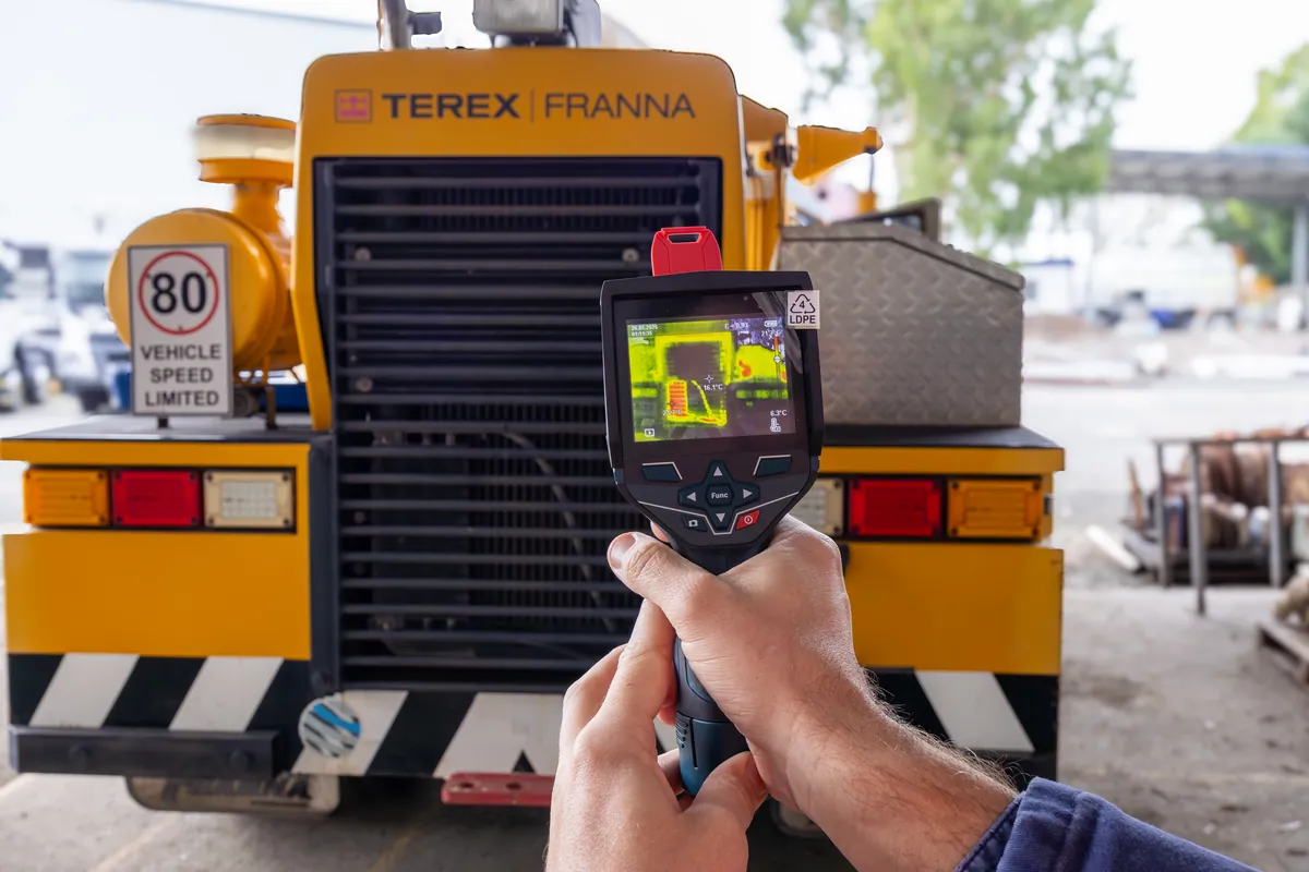 APEC technician holding a thermal imaging camera up to the front of a mobile crane